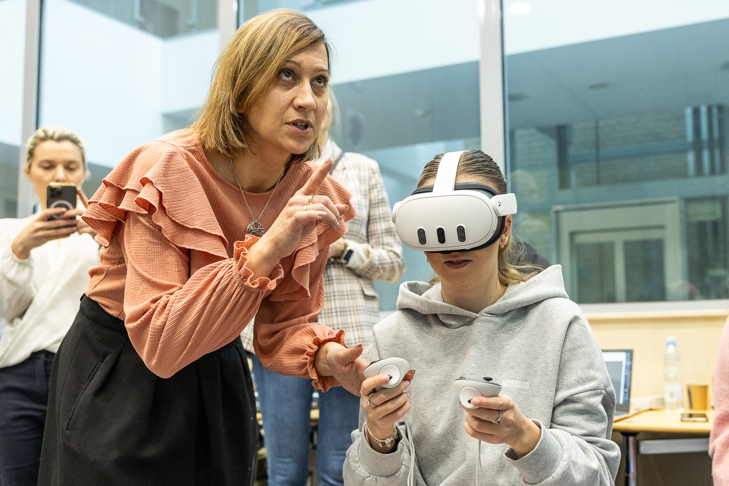 Nauczycielka wspiera uczennicę korzystającą z gogli VR.