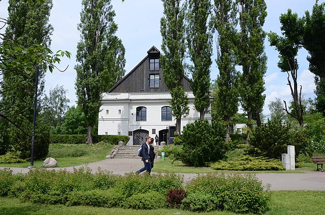 Biały budynek Muzeum Etnograficznego wśród drzew