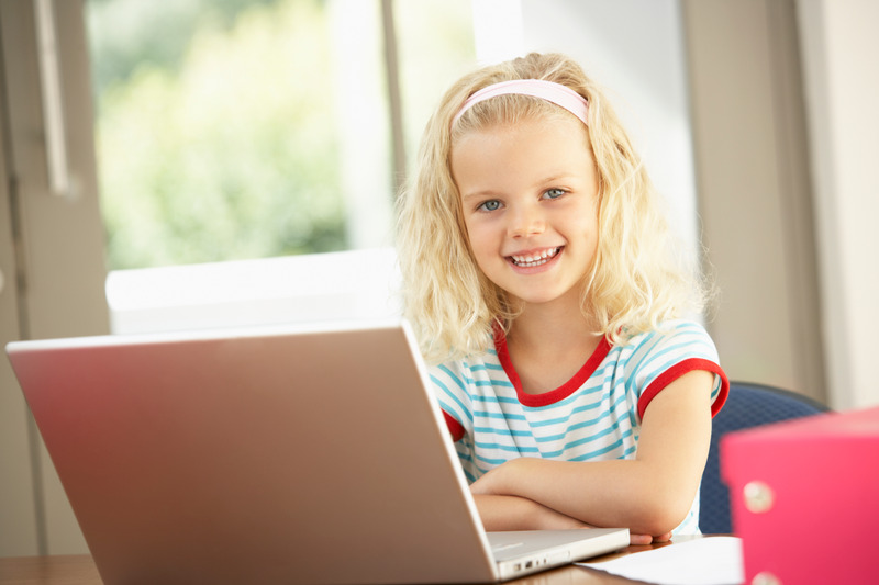 Dziewczynka uczy się w domu, korzystając z laptopa