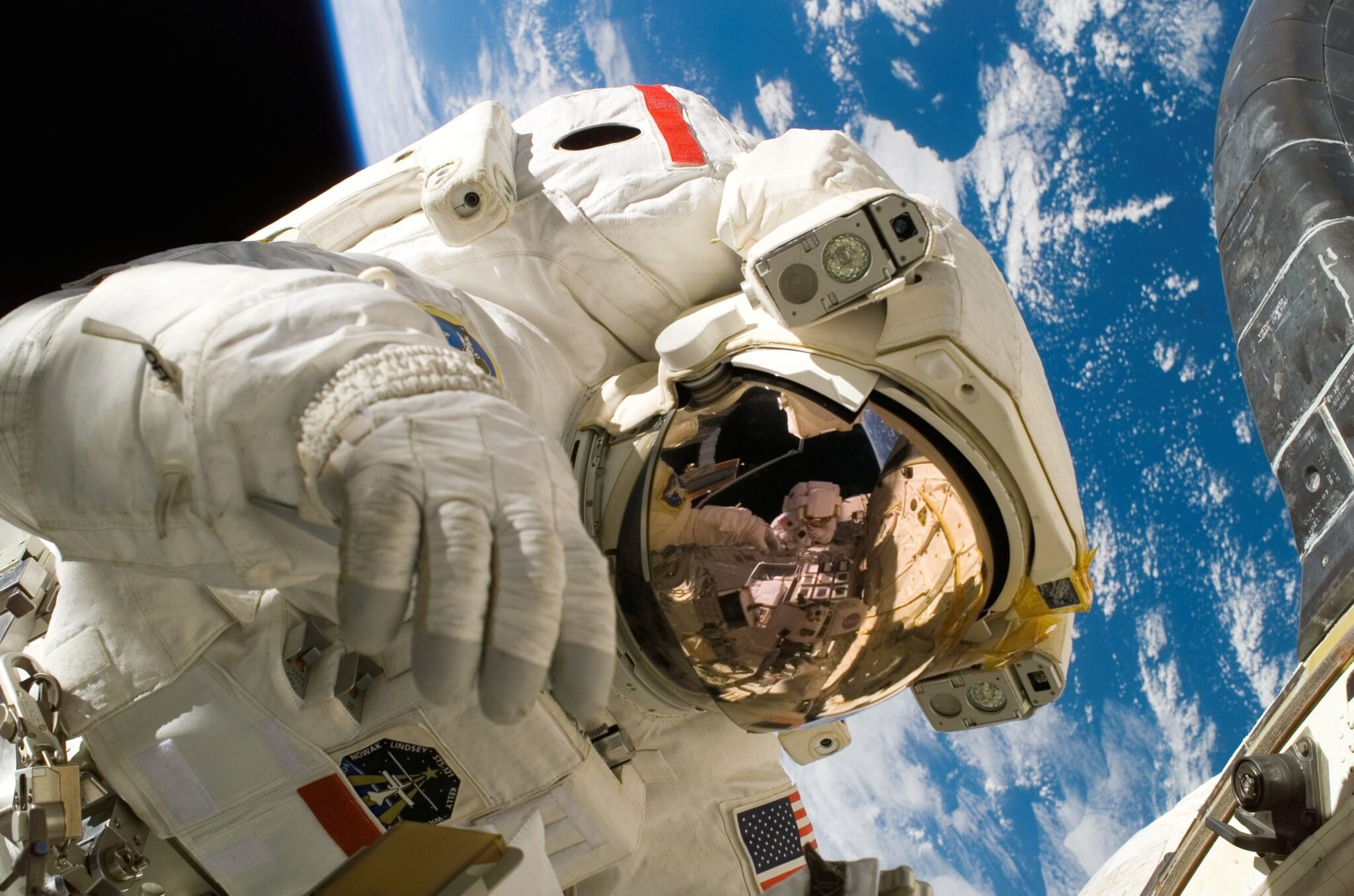 Astronauta podczas kosmicznego spaceru na tle odległej Ziemi.