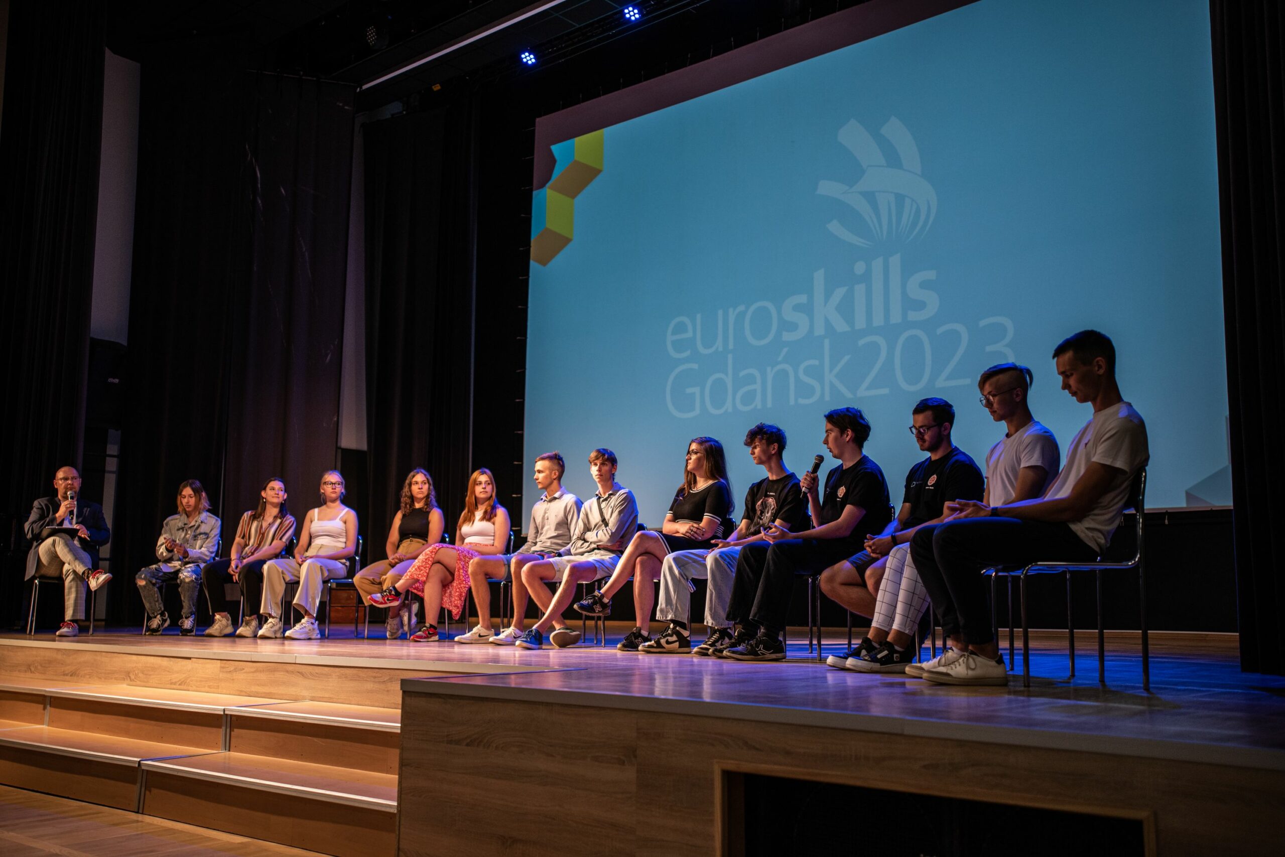 Młodzież na scenie przed dużym ekranem wyświetlającym napis EuroSkills Gdańsk2023.