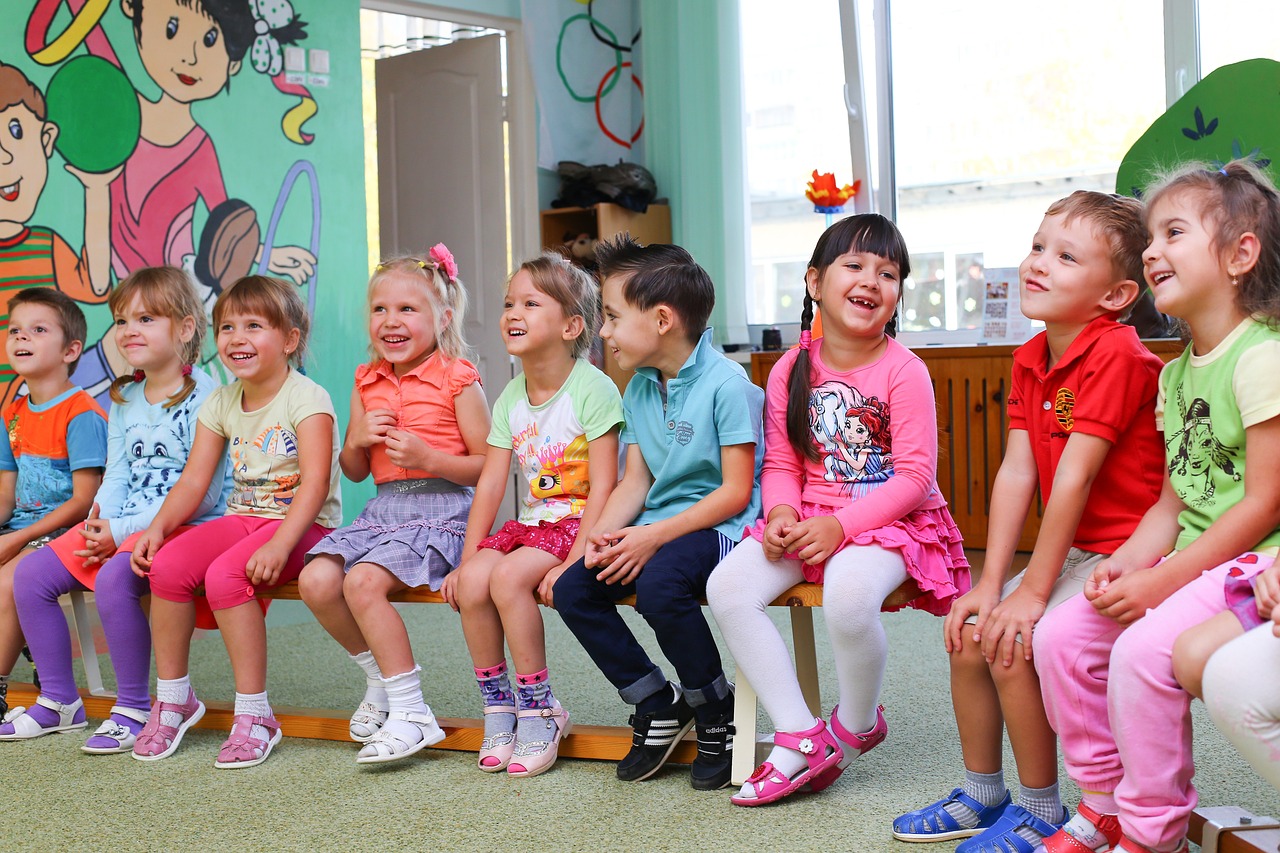 Uśmiechnięte dzieci siedzą na krzesełkach w kolorowej sali