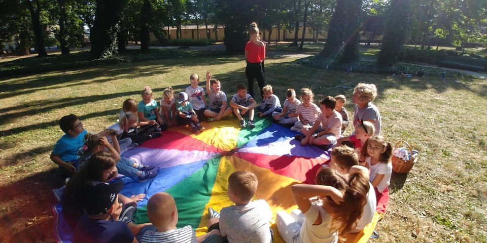 Dzieci siedzą na kolorowym kole podczas zabawy