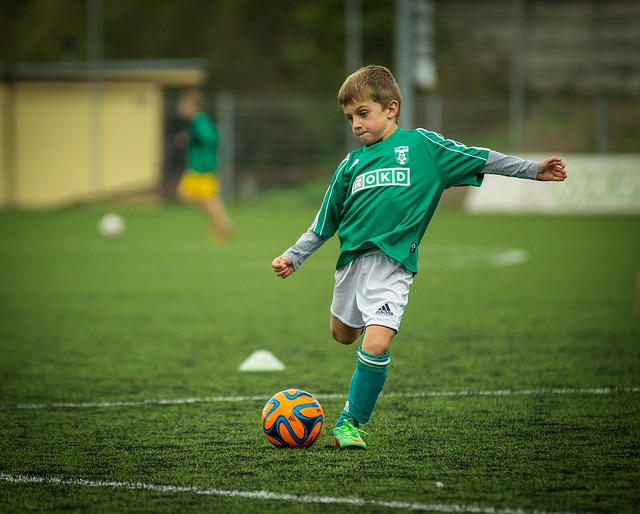 chłopiec gra w piłkę nożną na trawiastej murawie