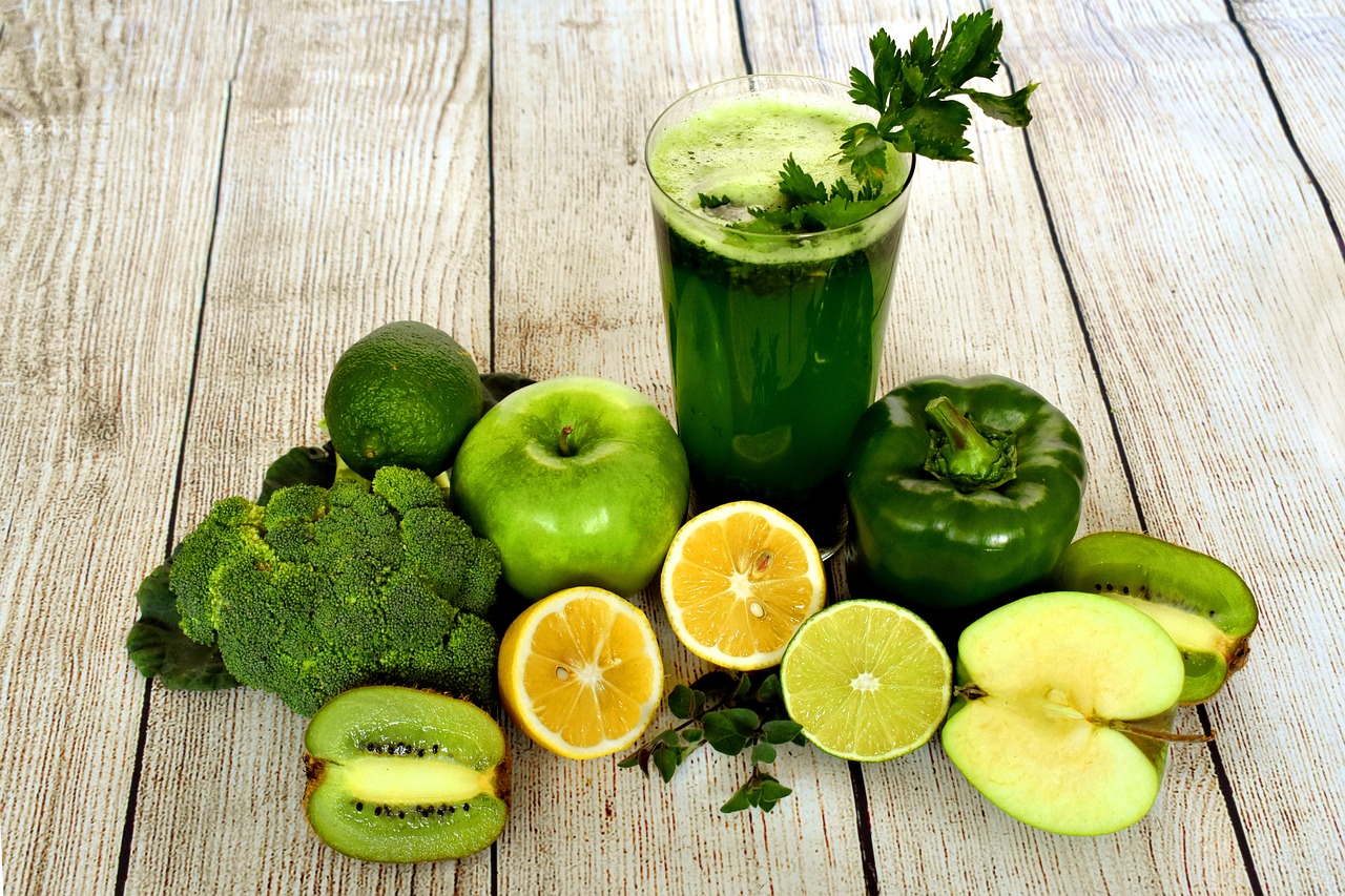 Zielony koktajl w otoczeniu owoców i warzyw.