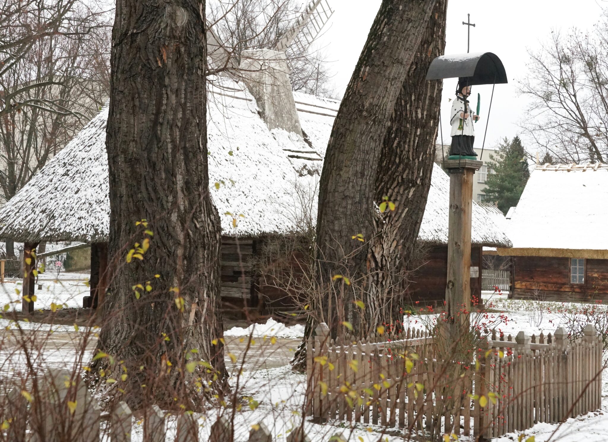 krajobraz zimowy: stare chaty wśród drzew