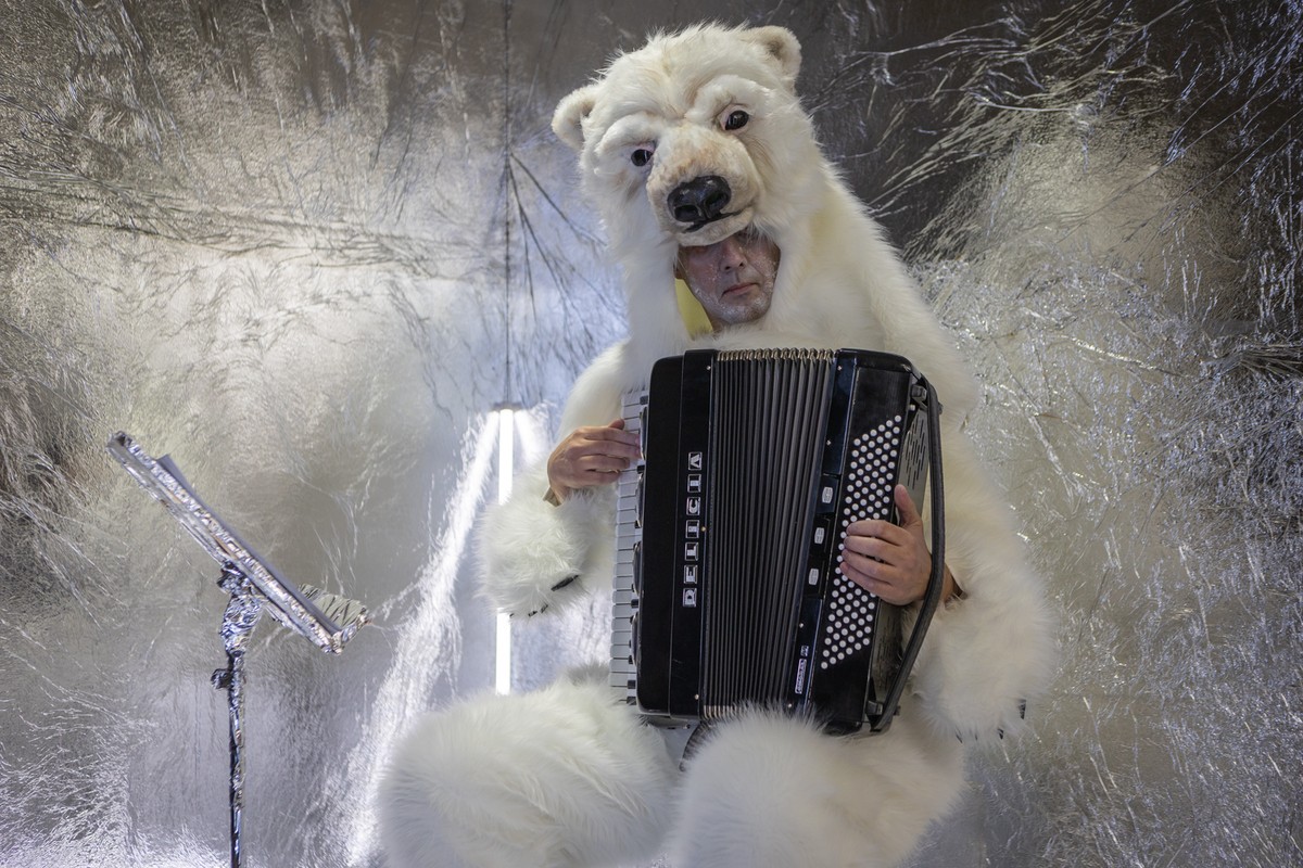 Aktor w skórze białego niedźwiedzia z akordeonem na kolanach.