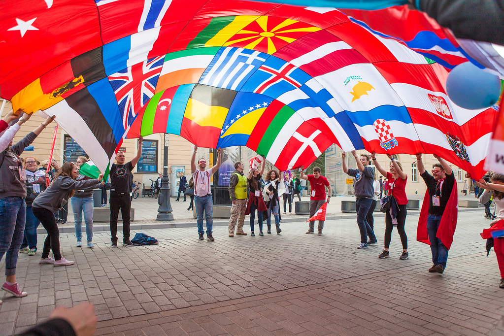 Młodzież studencka unosi połączone flagi wielu państw.