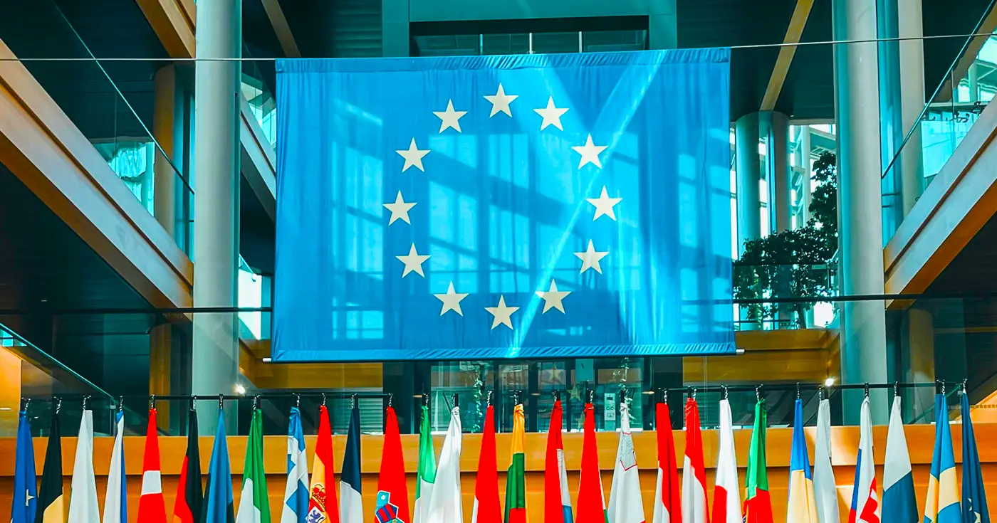 Rozwinięta flaga Unii Europejskiej i flagi na masztach krajów członkowskich.