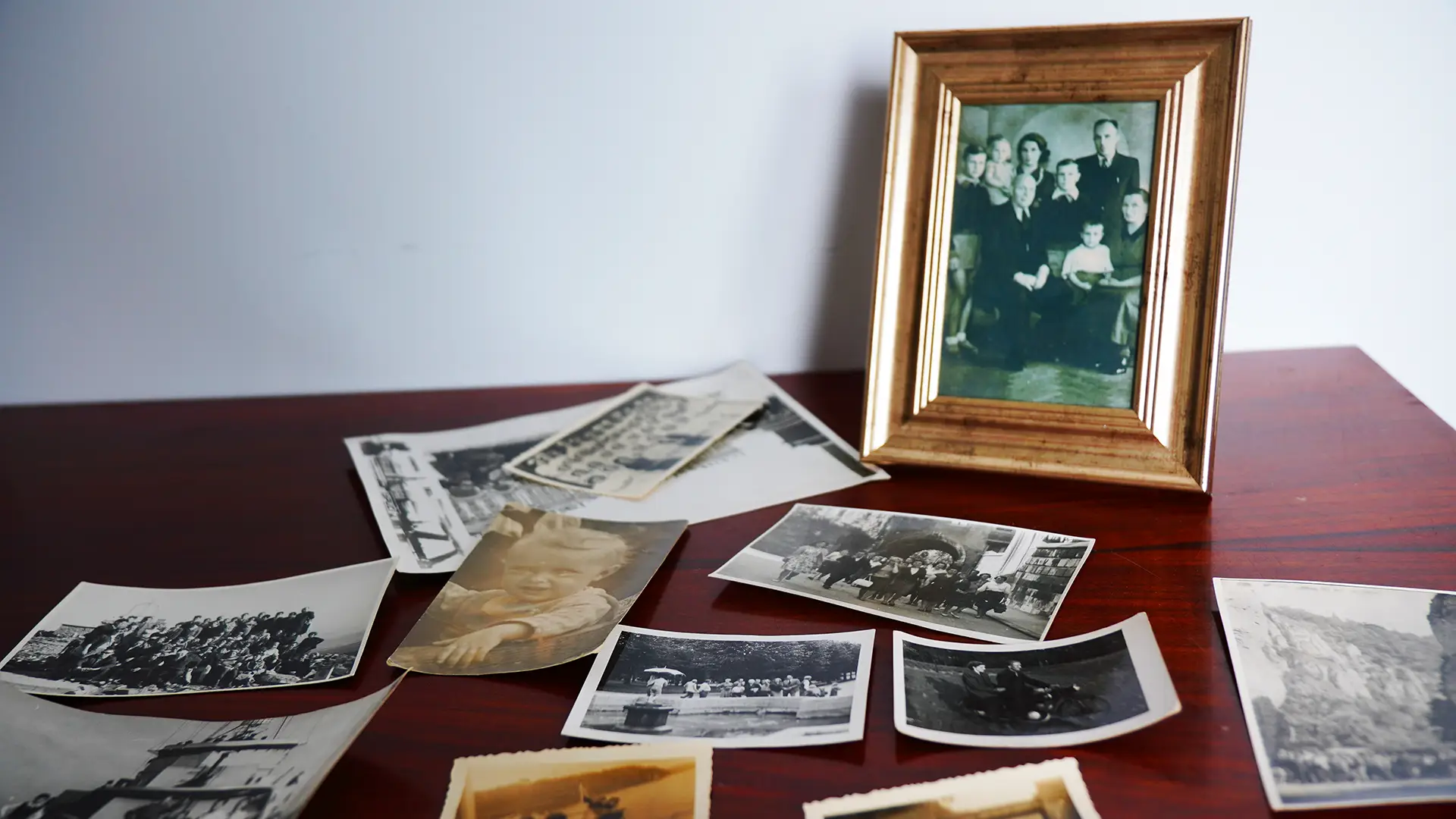 Ramka z zdjęciem rodzinnym oraz luźne stare fotografie na stoliku.