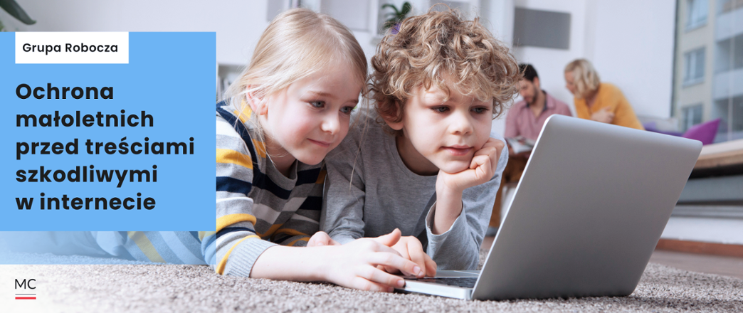 Mała dziewczynka i chłopiec leżą na dywanie wpatrzeni w ekran laptopa.