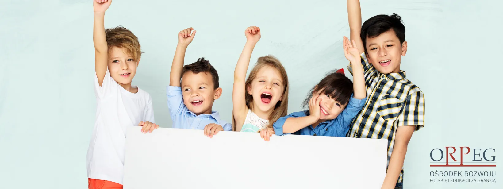 Pięcioro uśmiechniętych dzieci z podniesionymi rękami