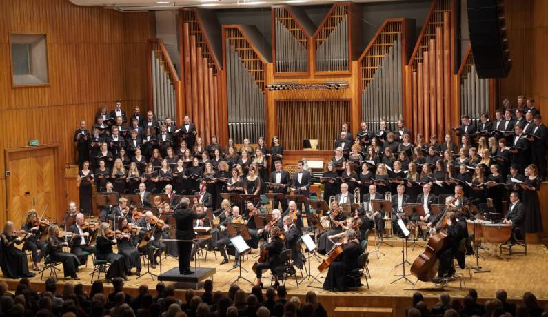 Orkiestra symfoniczna w filharmonii na tle organów.