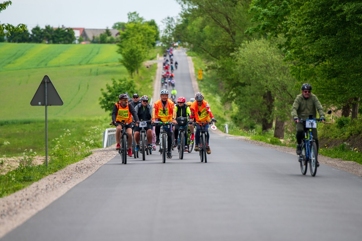 uczestnicy rajdu rowerowego jadą drogą w otoczeniu przyrody