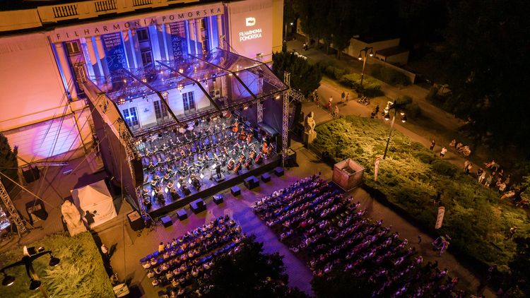 Fragment budynku filharmonii oraz koncert plenerowy z publicznością.