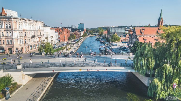 Widok na rzekę, most i zabudowę miejską.