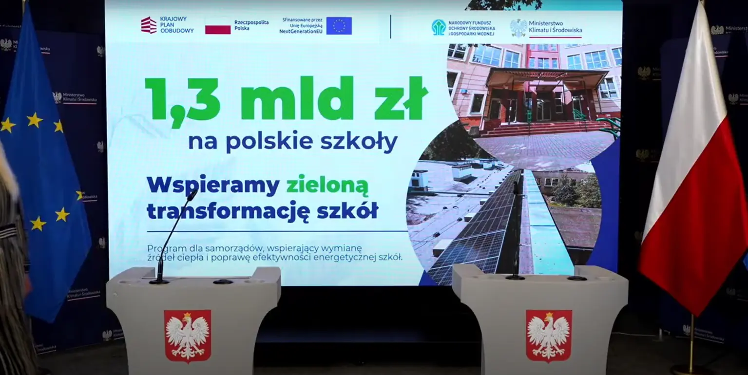 Pomiędzy flagami UE i polską ekran wyświetla informacje o wsparciu rządu kwotą 1,3 mld na zieloną transformację.