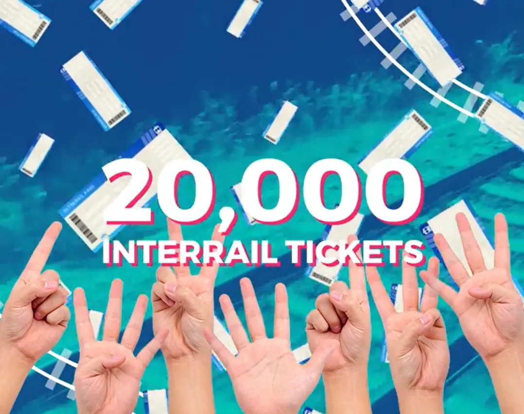 Uniesione dłonie. Napis 20 000 interrail tickets.