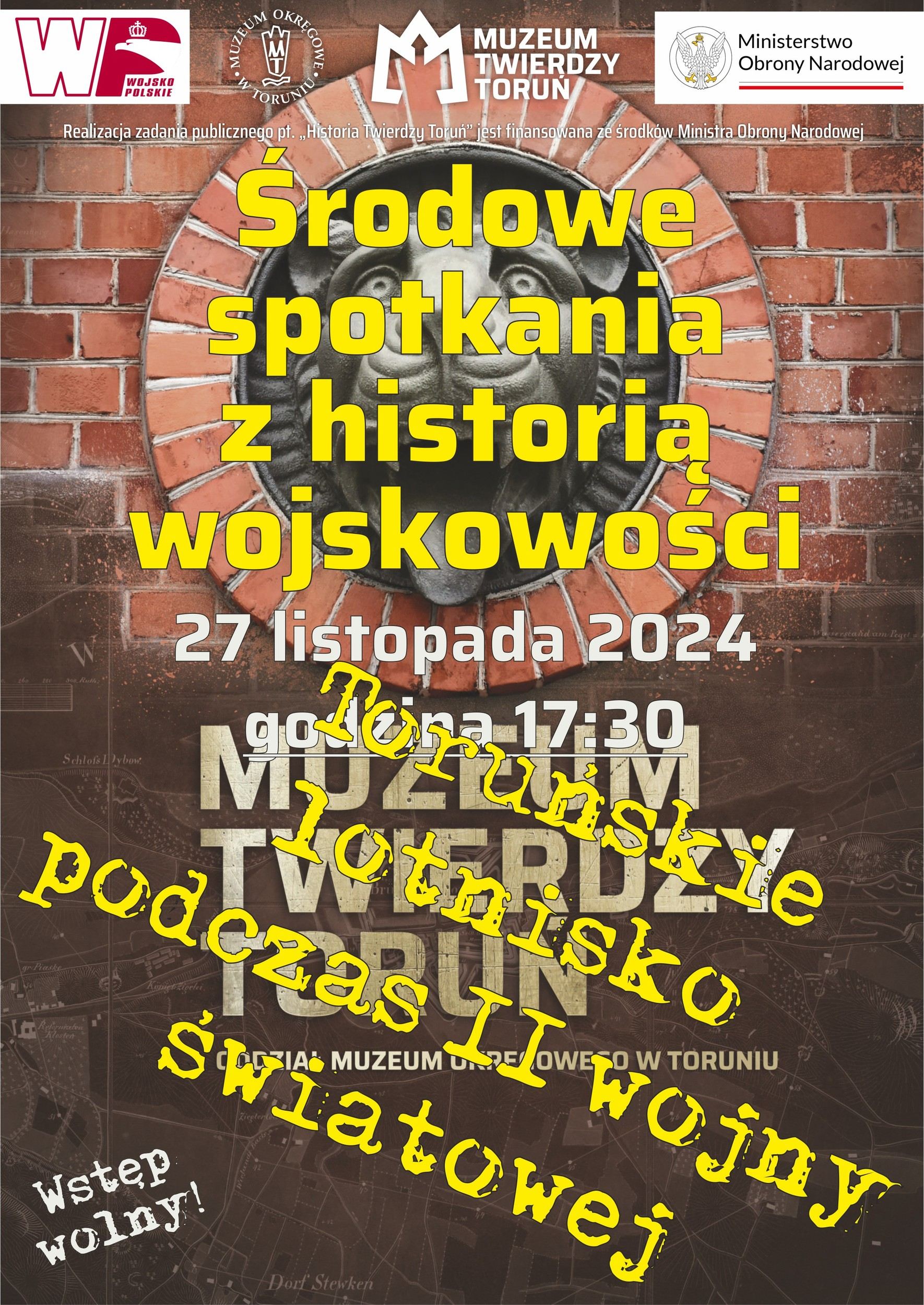 Plakat informujący o wydarzeniu, w tle ściana z czerwonej cegły, na pierwszym planie napisy.