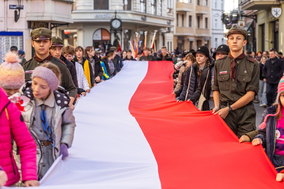 harcerze niosą długą rozciągniętą na płasko biało-czerwoną flagę przez deptak miasta