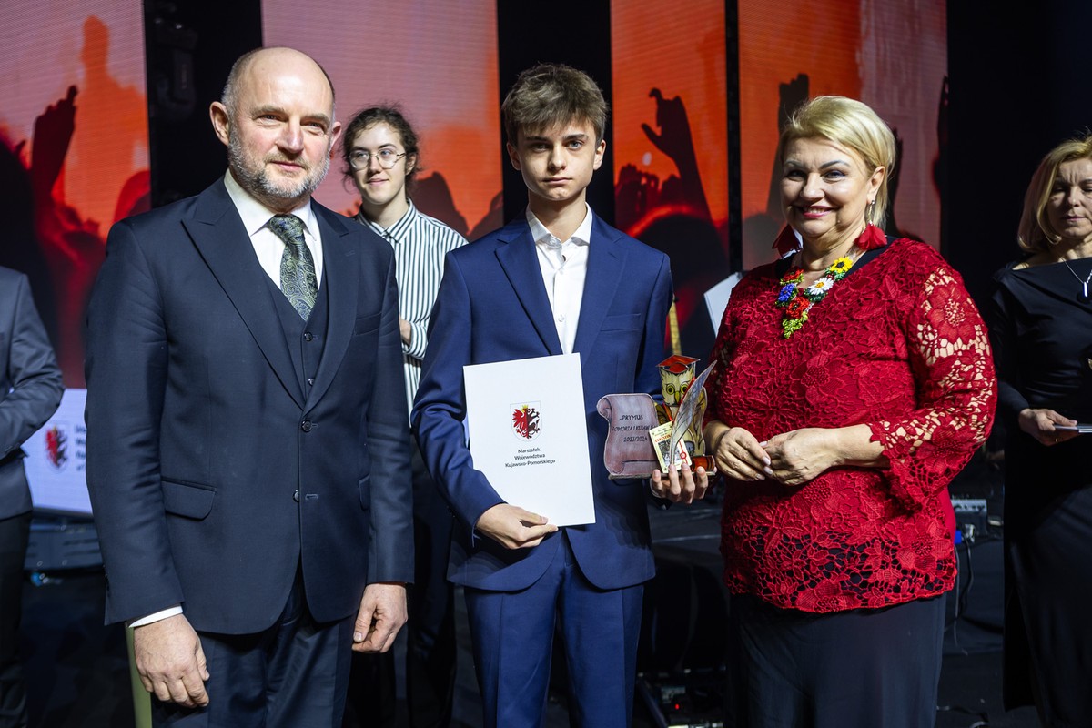 Uczeń uhonorowany nagrodą marszałka województwa kujawsko-pomorskiego w otoczeniu dwóch osób